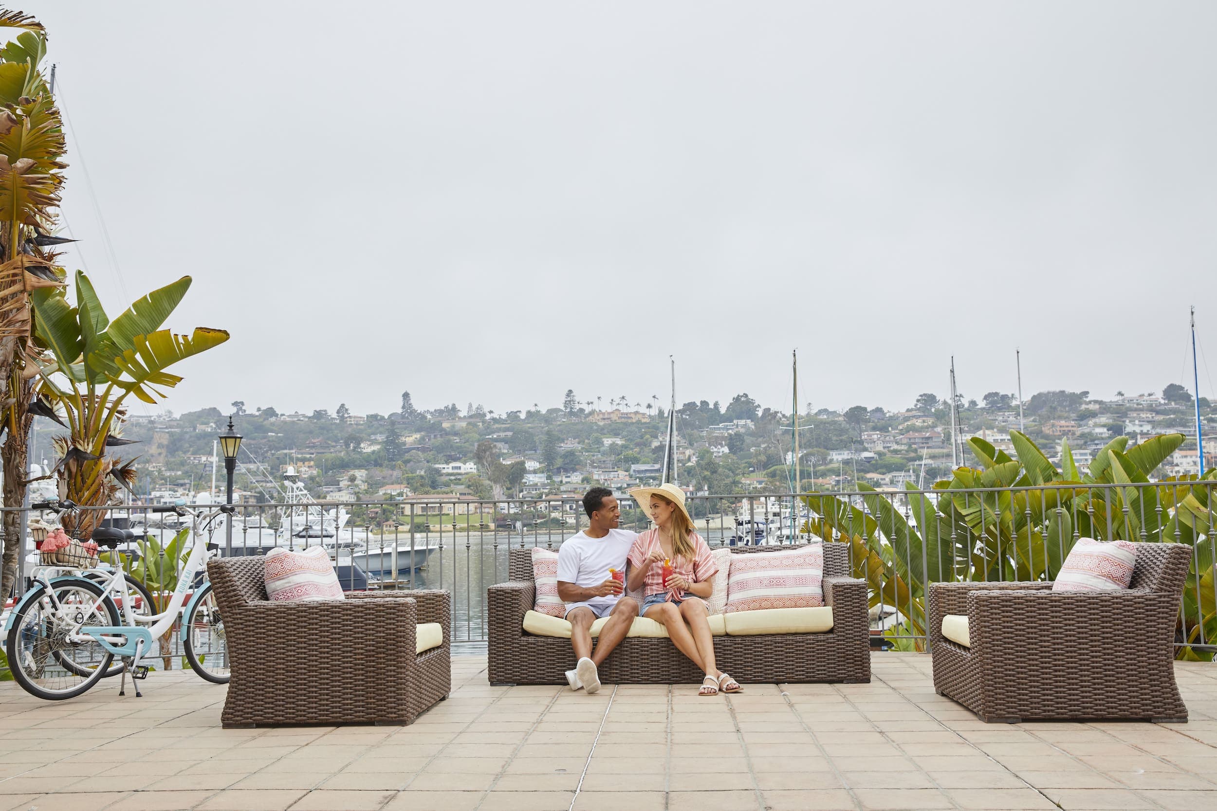 A couple sitting on a patio furniture by the water at Kona Kai