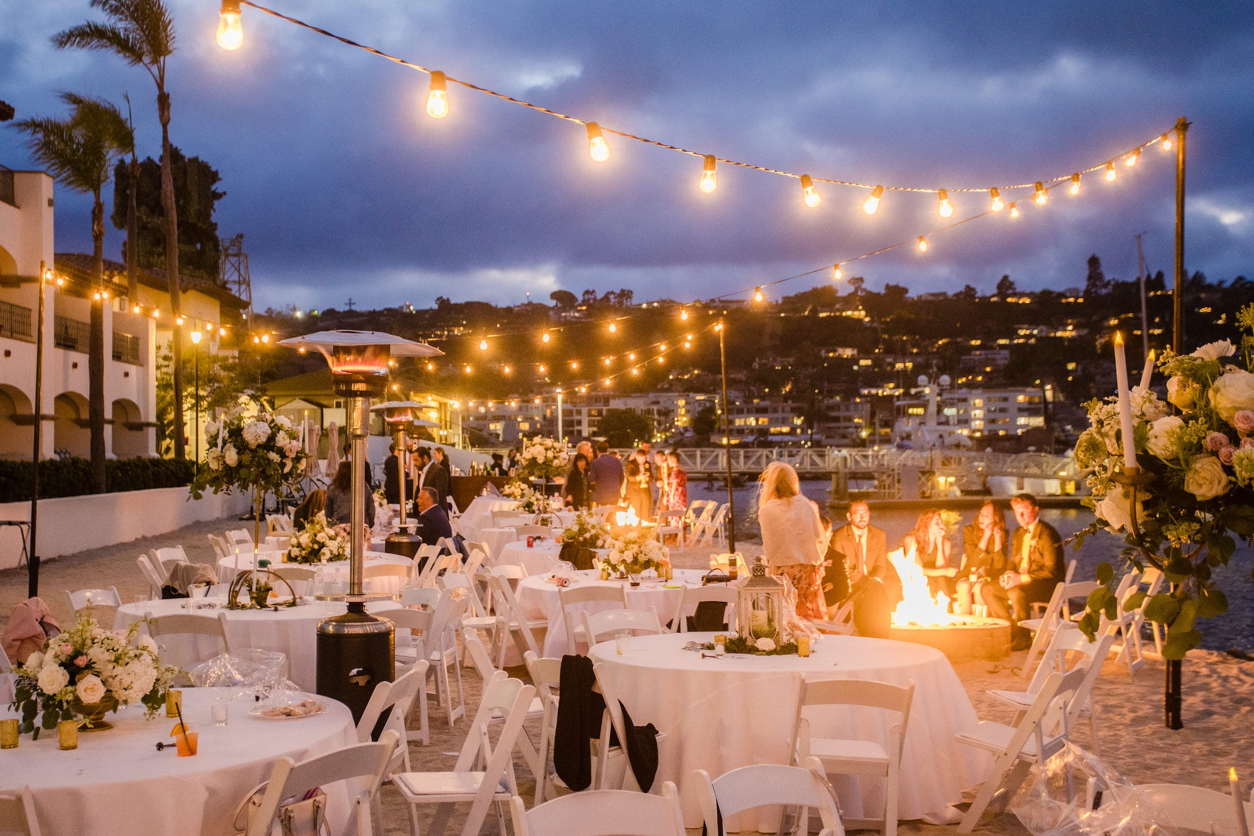 A large group of people on the beach at night during a wedding