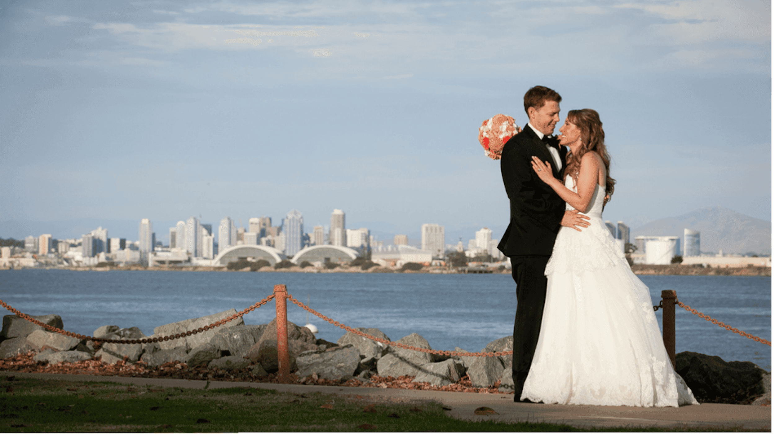 A newly wed couple embracing by the water