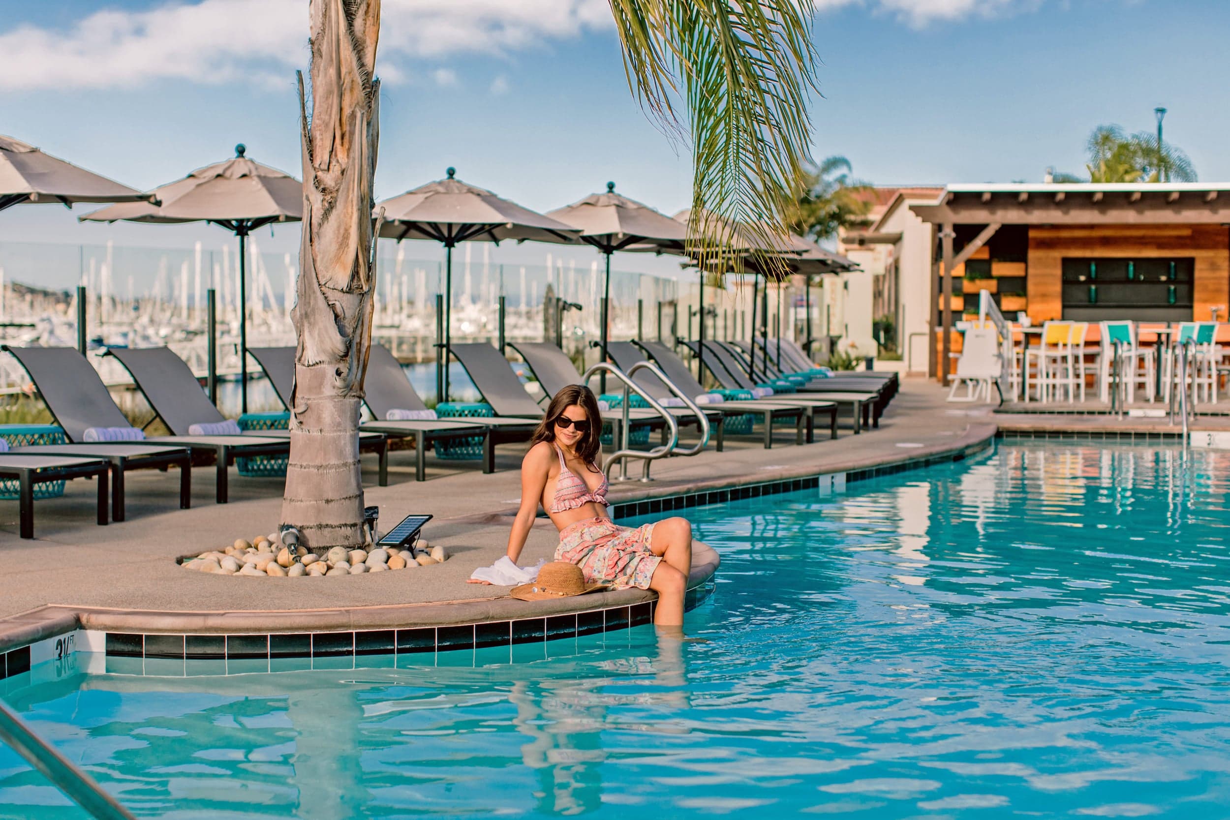 A woman sitting poolside with her feet in the pool at Kona Kai