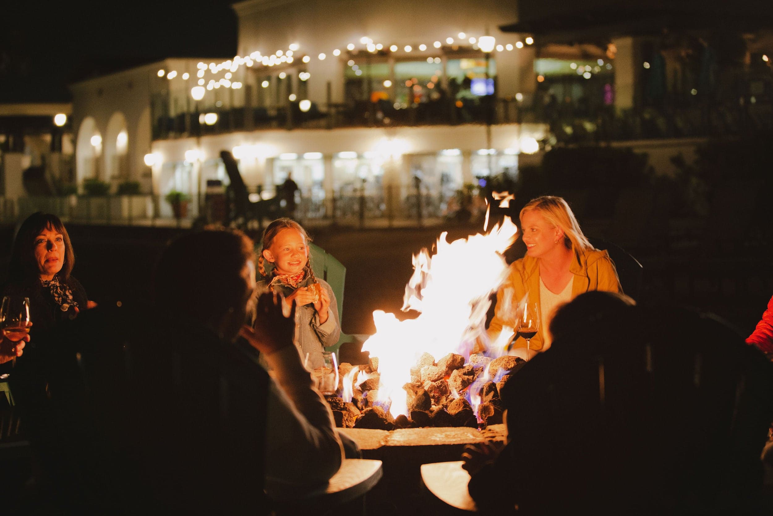 A group of people around a fire pit making S'mores at night