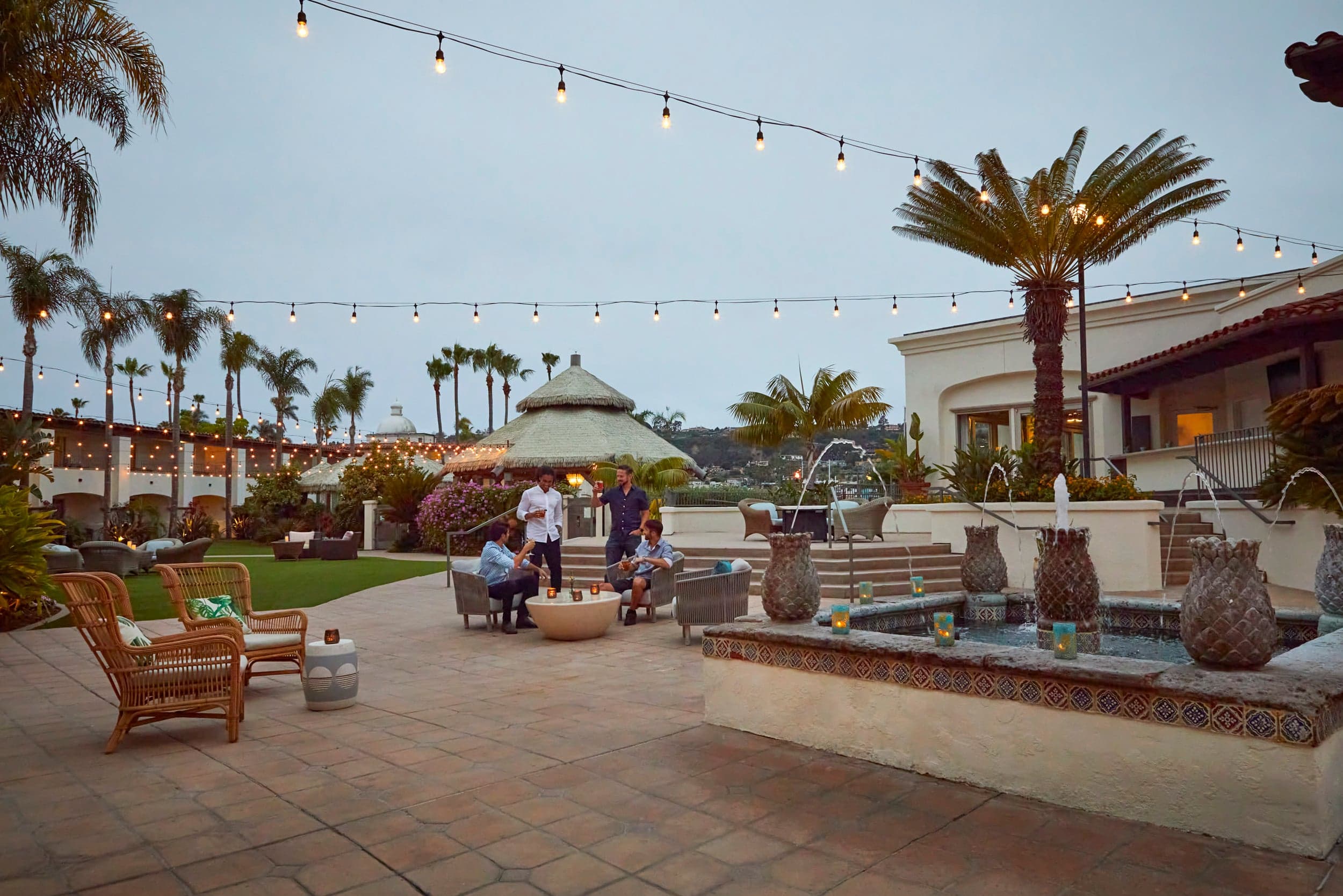 A group of people by a fire pit having some drinks