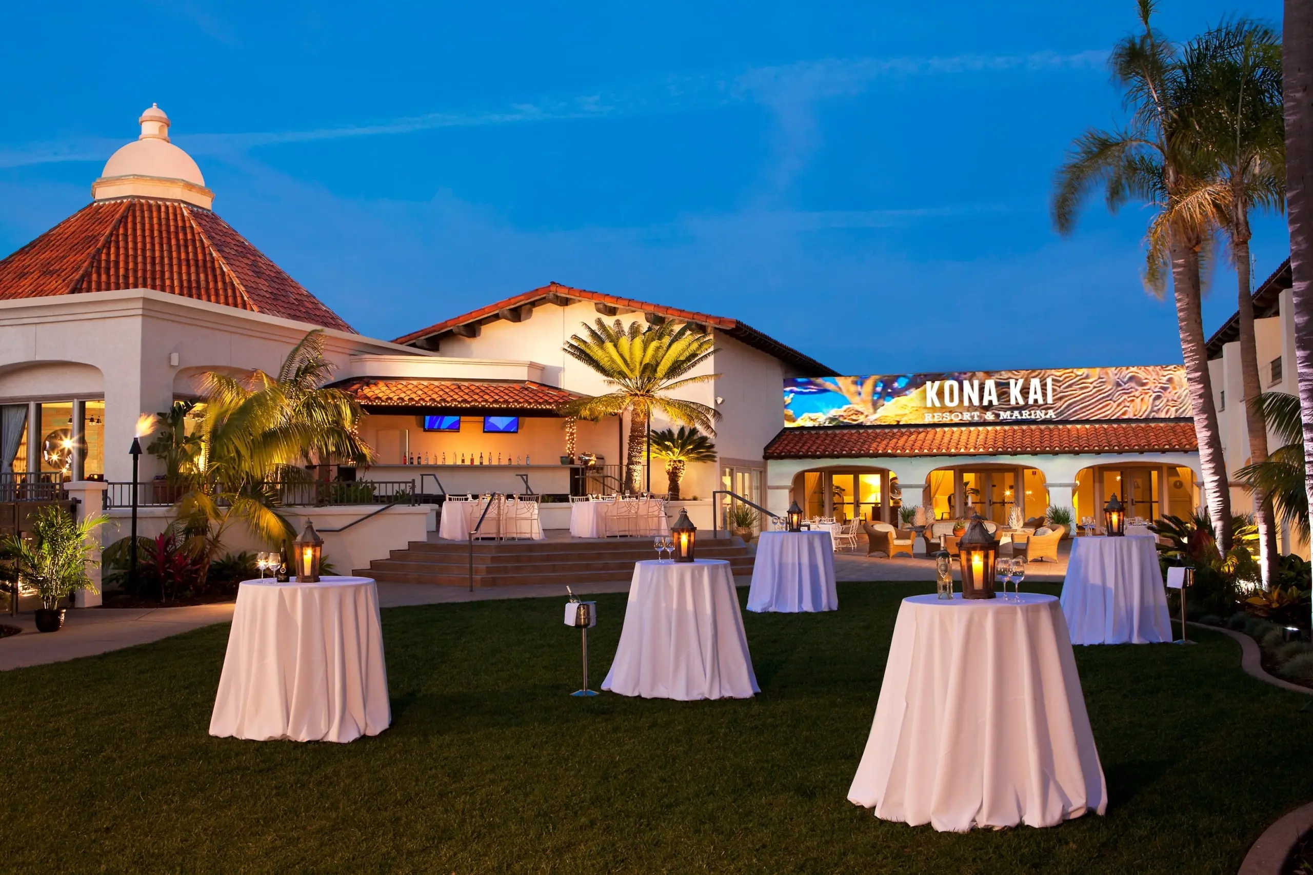The Cabo Courtyard at Kona Kai, set up for a nighttime cocktail reception with tall cruiser tables topped with white table cloths