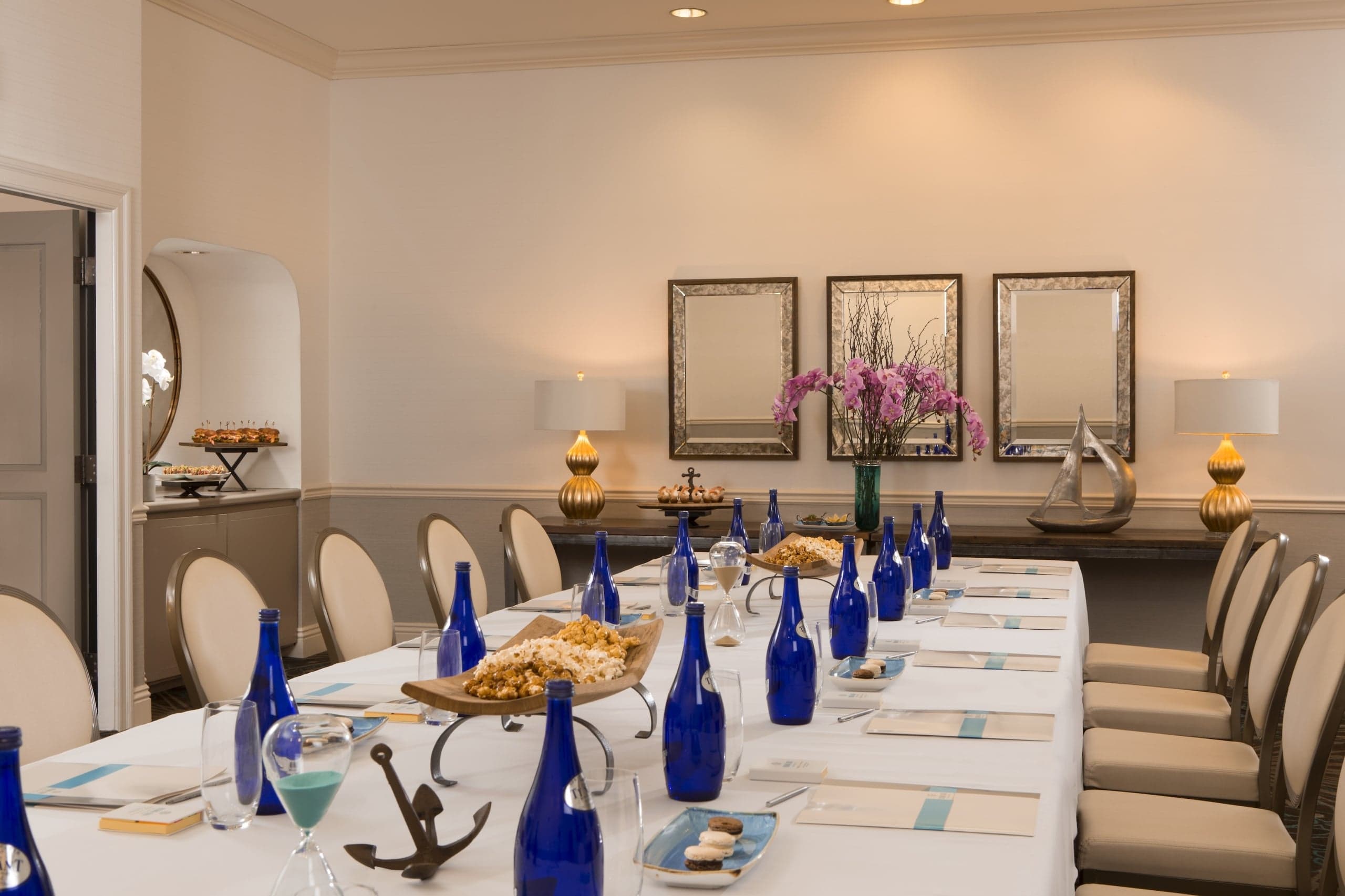 Kona Kai's La Jolla room, set up for a meeting with a long table topped with a white table cloth, centre pieces and blue water bottles