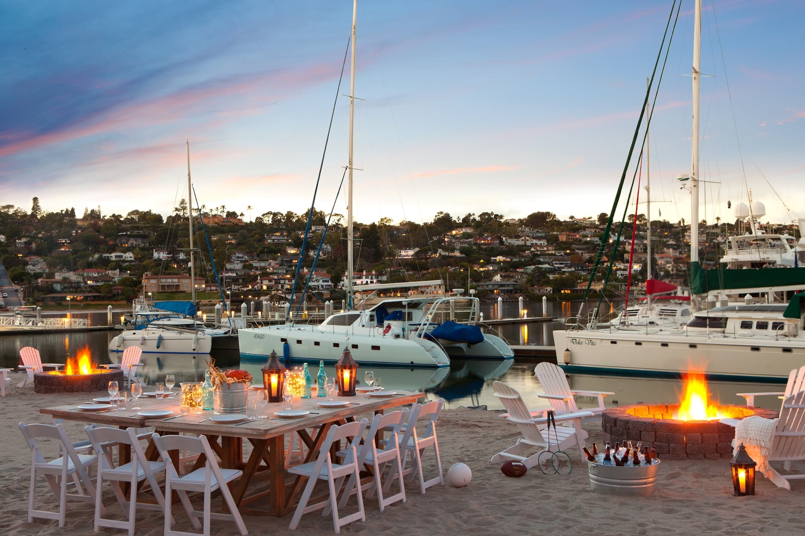 Kona Kai's private beach, set up for a reception at night, with lanterns topping large wood tables surrounded by folding chairs
