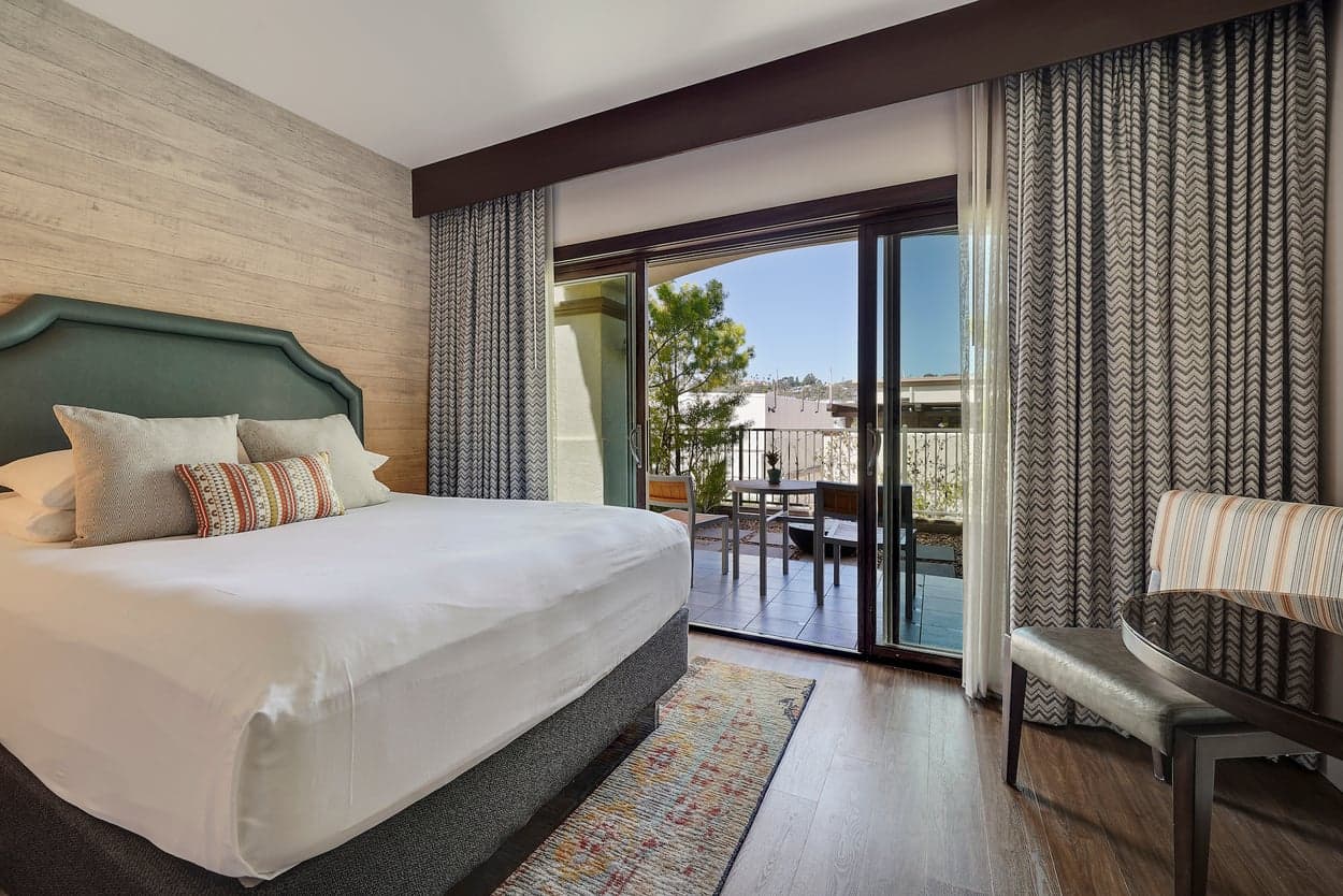 A Junior Suite at Kona Kai with a king bed, table and two chair, and access to a private patio with a fire pit
