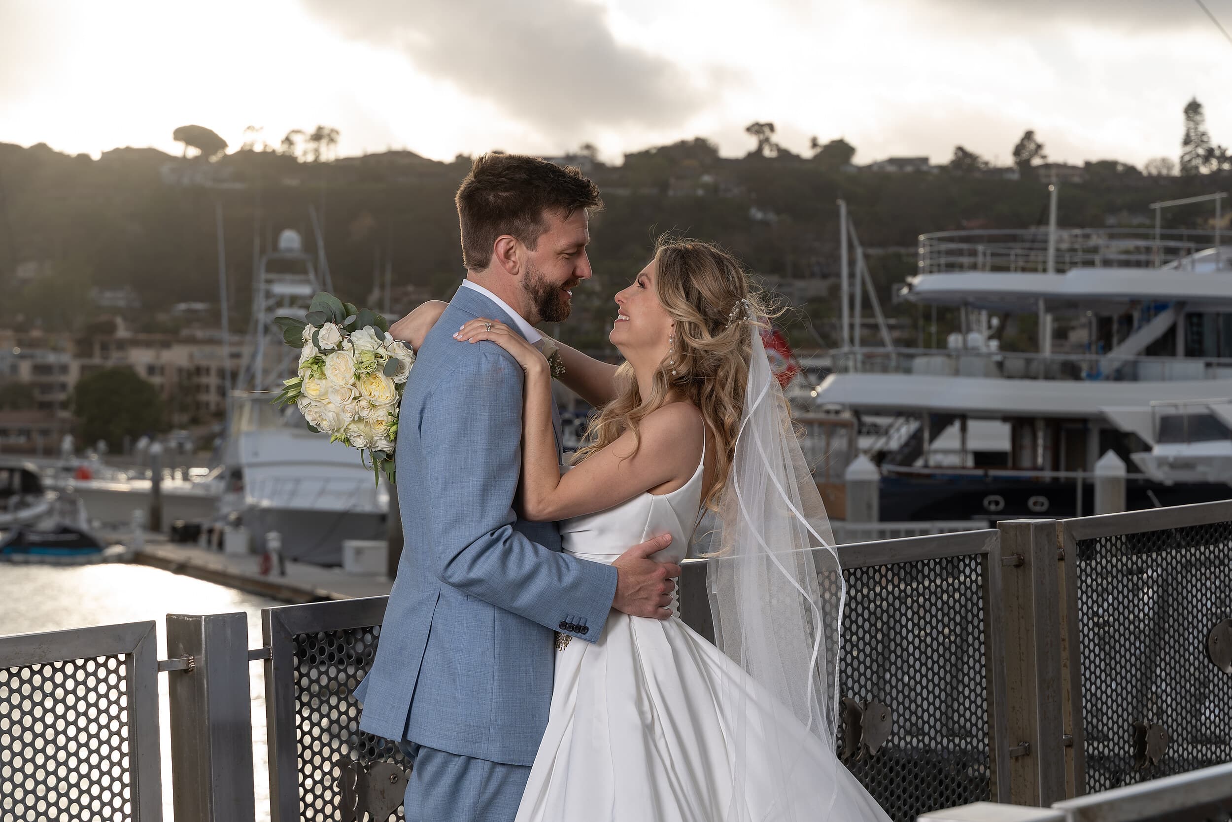 Bride and groom embracing at sunset on the marina at Kona Kai Resort & Spa on Shelter Island, San Diego