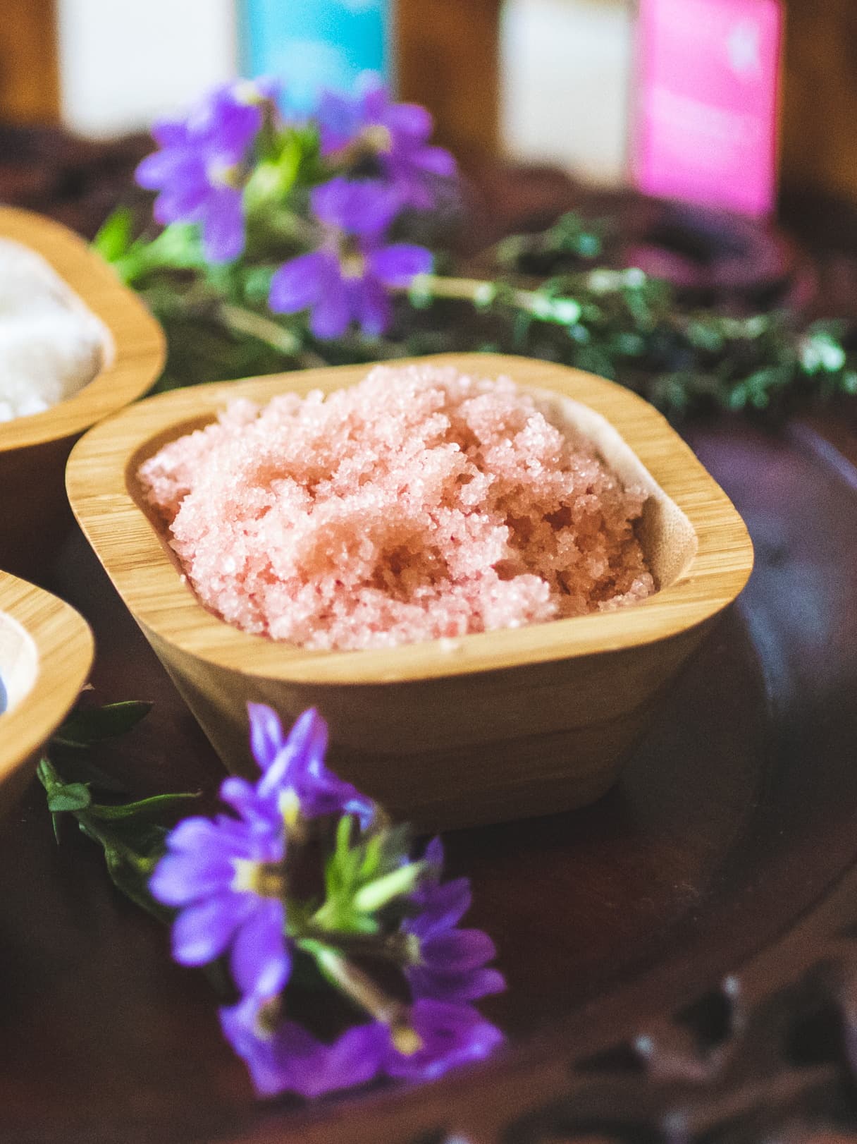 Pink Himalayan salt body scrub in a bamboo bowl with fresh purple blooms at the spa at Kona Kai Resort & Spa on Shelter Island, San Diego