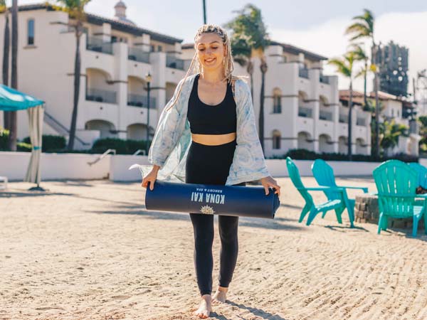 Lady On The Beach With A Yoga Mat.